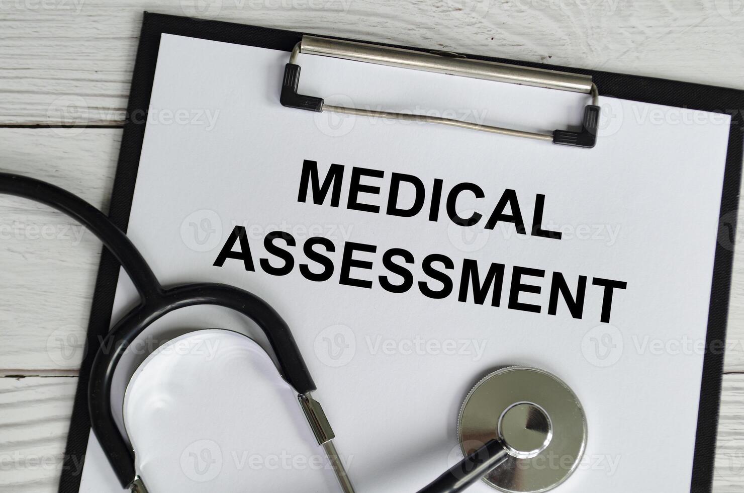 Top view of Medical Assessment Text on white paper clipboard with stethoscope on wooden table background. Health and medical concept. photo