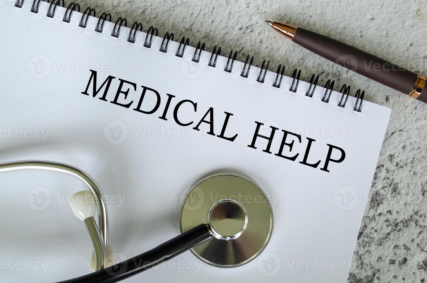 Top view of Medical Help text on white paper notepad with stethoscope on wooden table background. Health and medical concept. photo