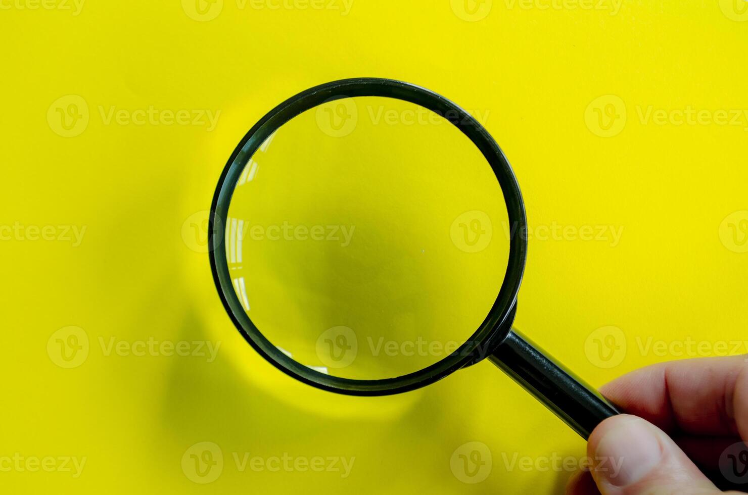 Top view of a magnifying glass against a bright yellow background. Searching, examining, focusing or investigation concept.. photo