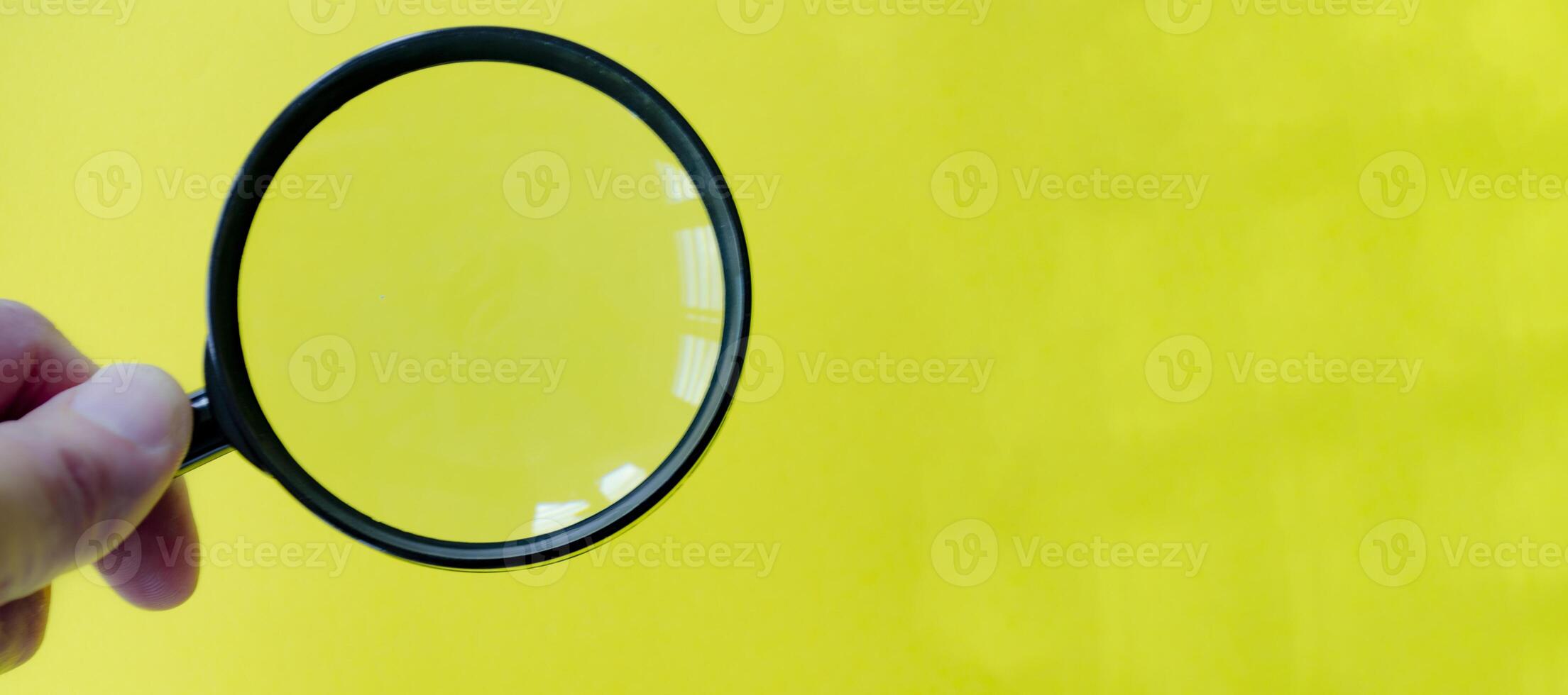 A magnifying glass against a bright yellow background. Searching, examining, focusing or investigation concept photo