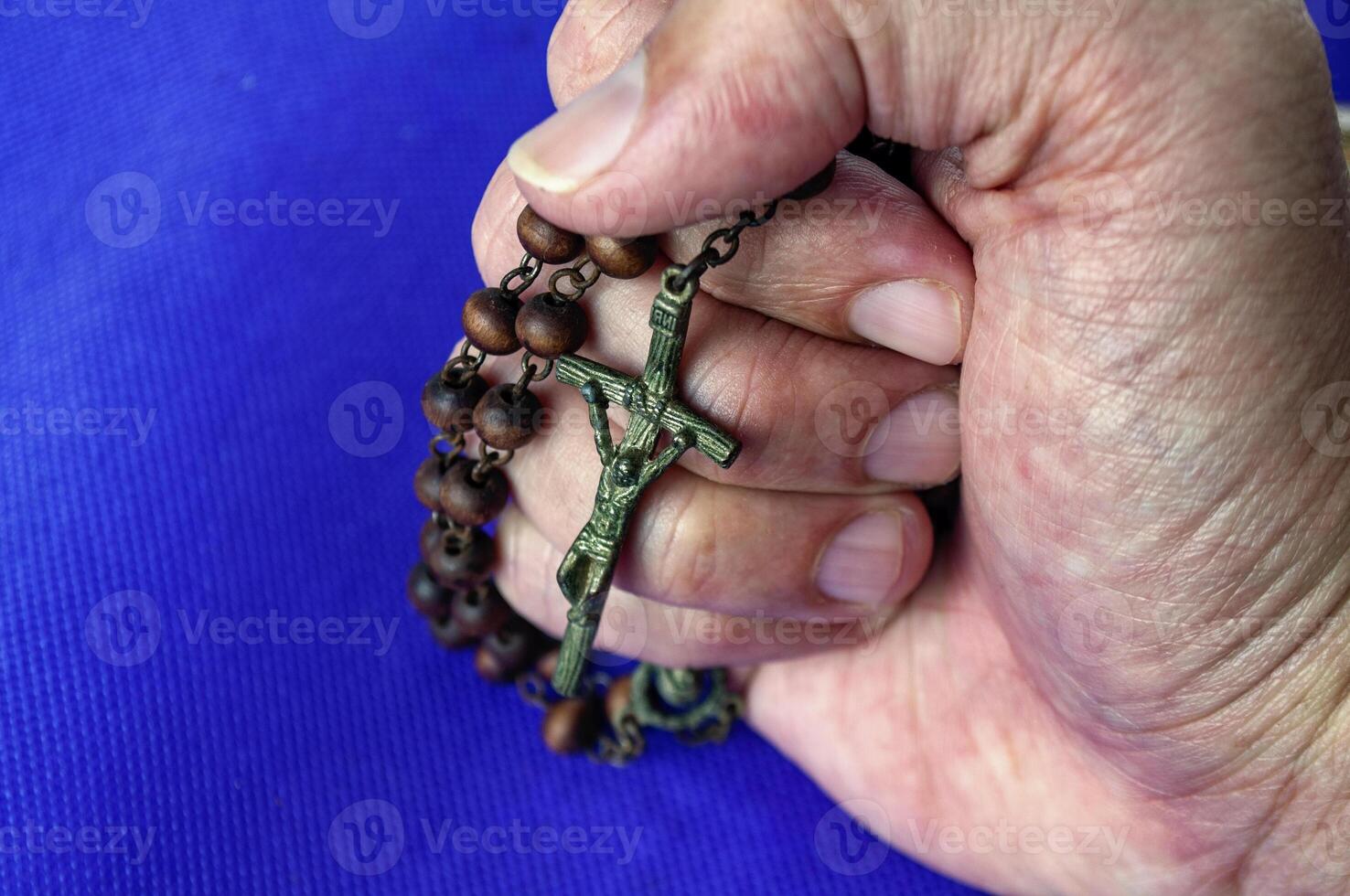 A hand holding a beaded Rosary reveals trust placed in prayer and heaven strength during trials. photo