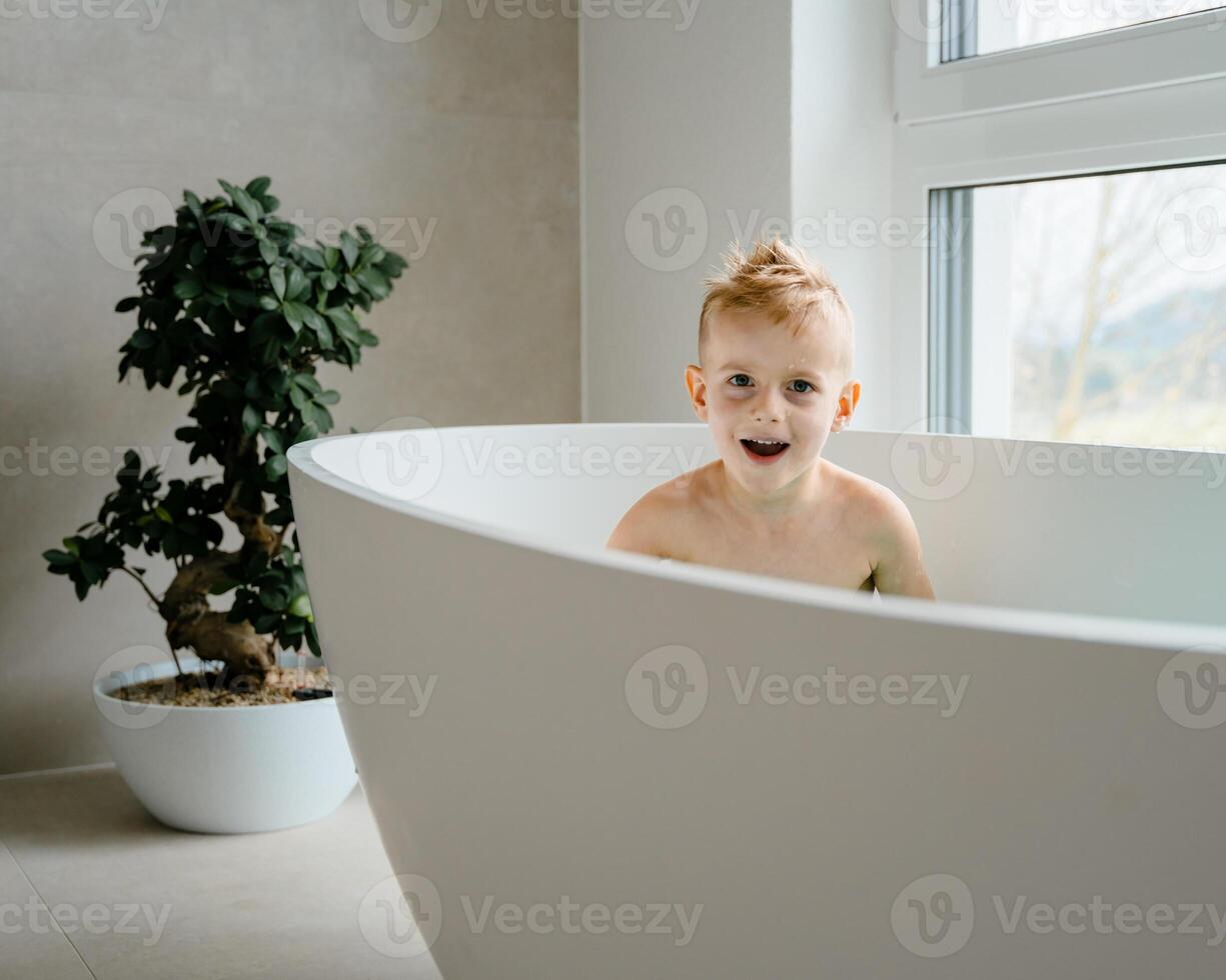 In a calm, sunlit bathroom, a young child enjoys his bath, splashing water and giggling as rubber ducks float by, the soft echo of his laughter bouncing off the tiled walls. photo
