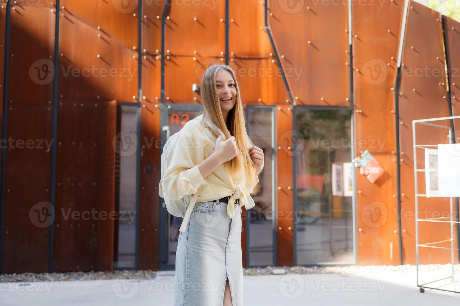 Young woman enjoying her day outside a modern building while smiling in a sunny urban setting photo