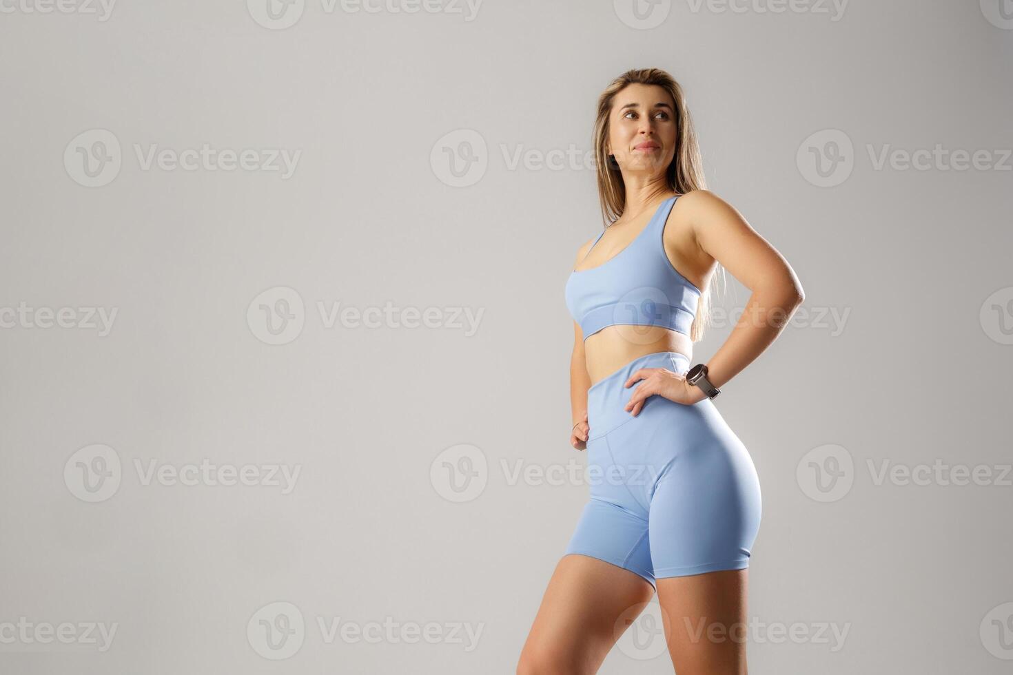 Confident woman posing in comfortable athletic wear during a fitness photoshoot in a simple studio setting photo