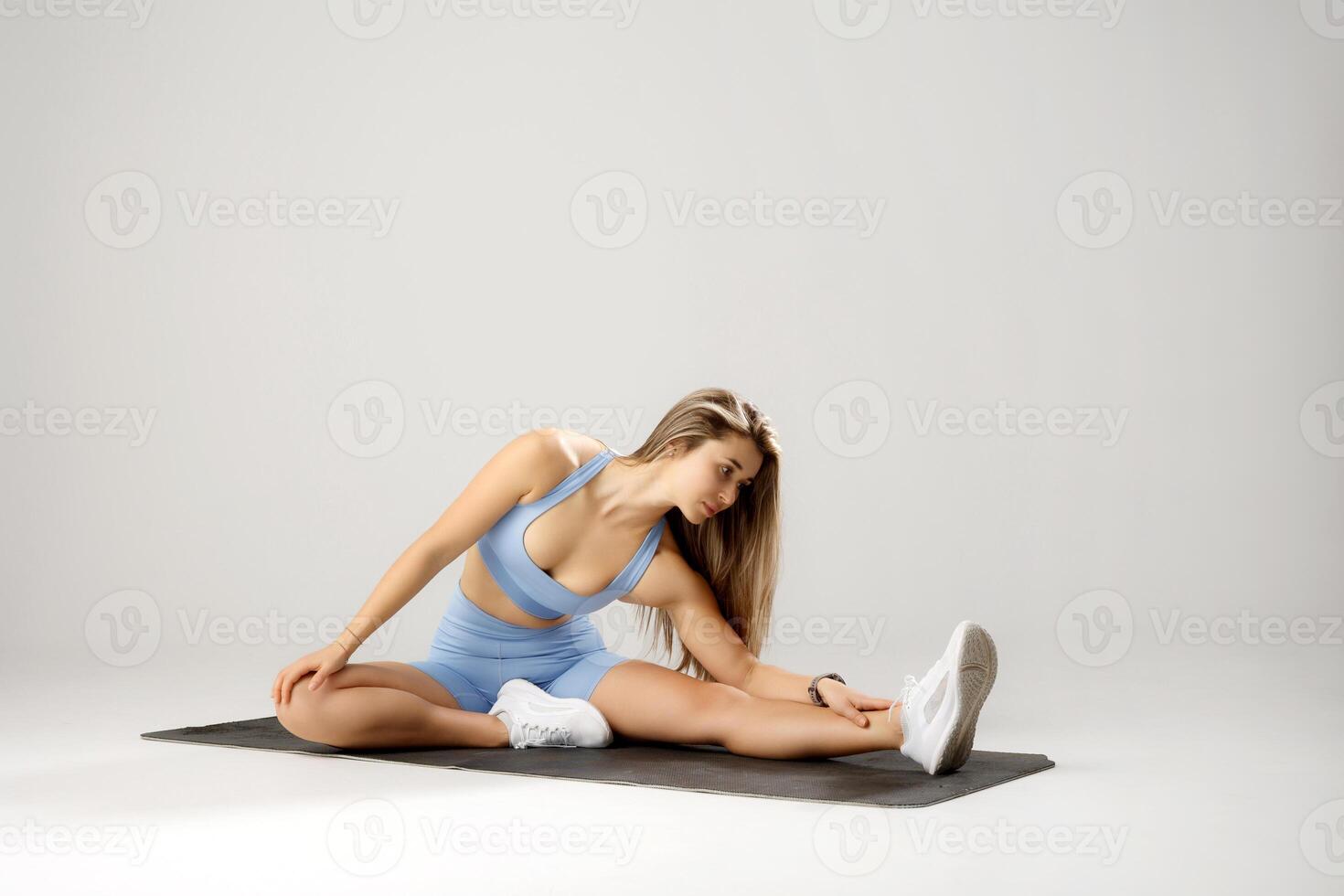 Fitness enthusiast stretching on a yoga mat during a workout session in a bright studio environment photo