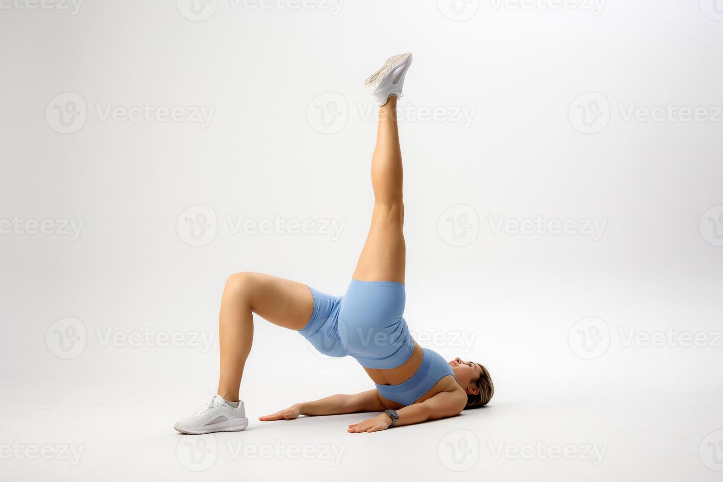 Fitness enthusiast performs bridge pose with raised leg indoors in minimalistic atmosphere during workout session photo