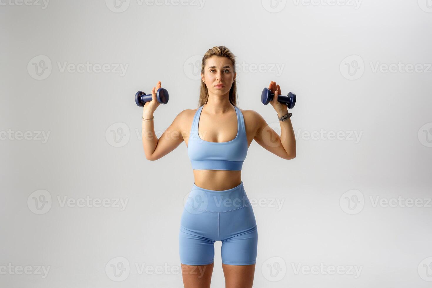 Woman exercising with dumbbells in a workout studio, focused on strength training for health and fitness improvement photo