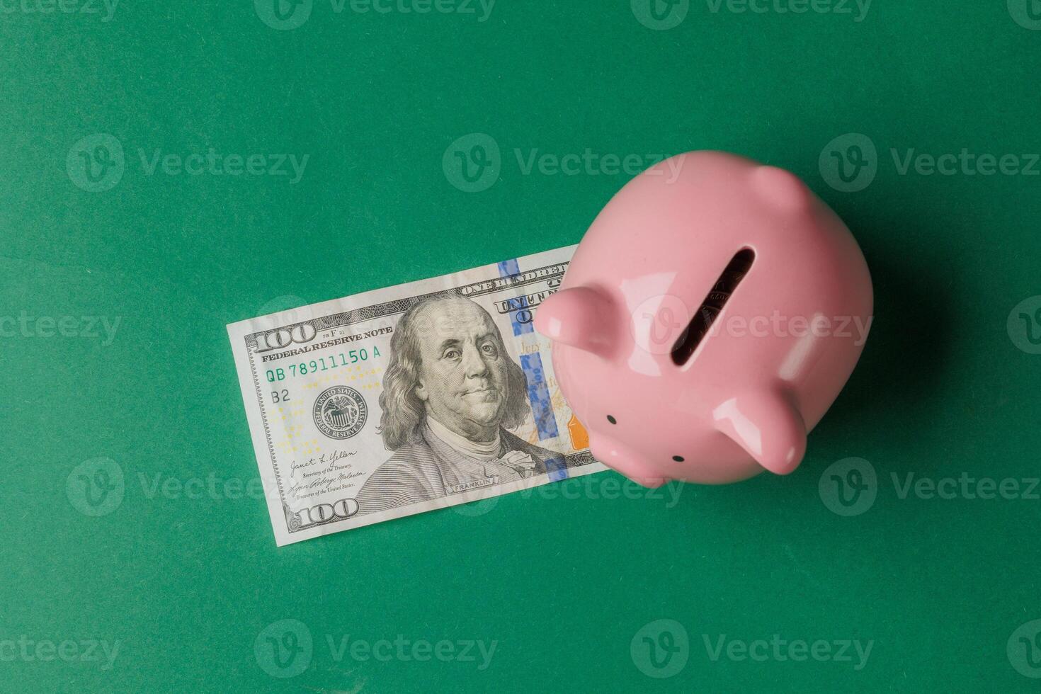 Money-saving piggy bank with a hundred-dollar bill on a green background photo