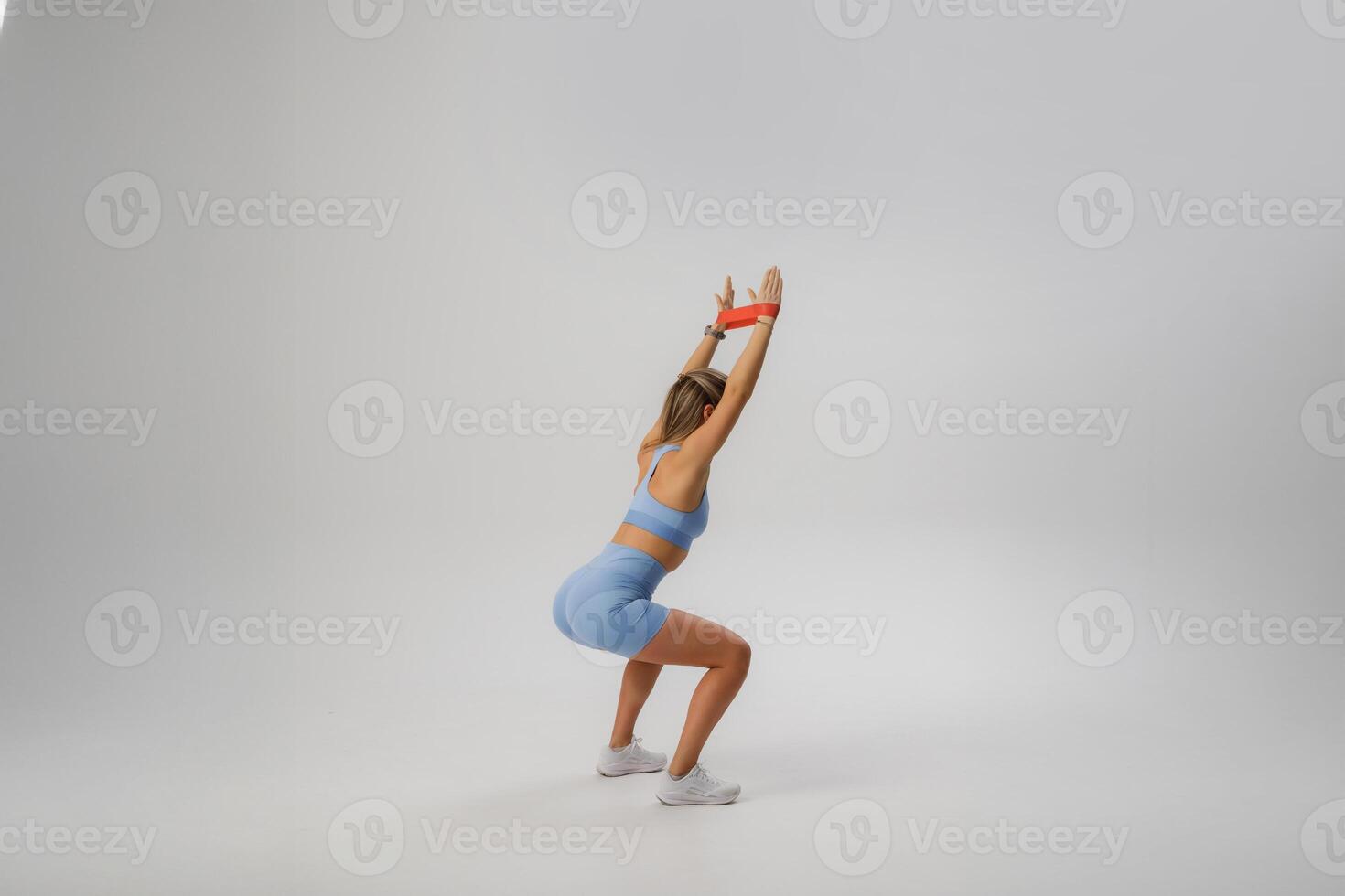 Fitness enthusiast demonstrating a squat exercise in a spacious studio setting while wearing workout attire photo