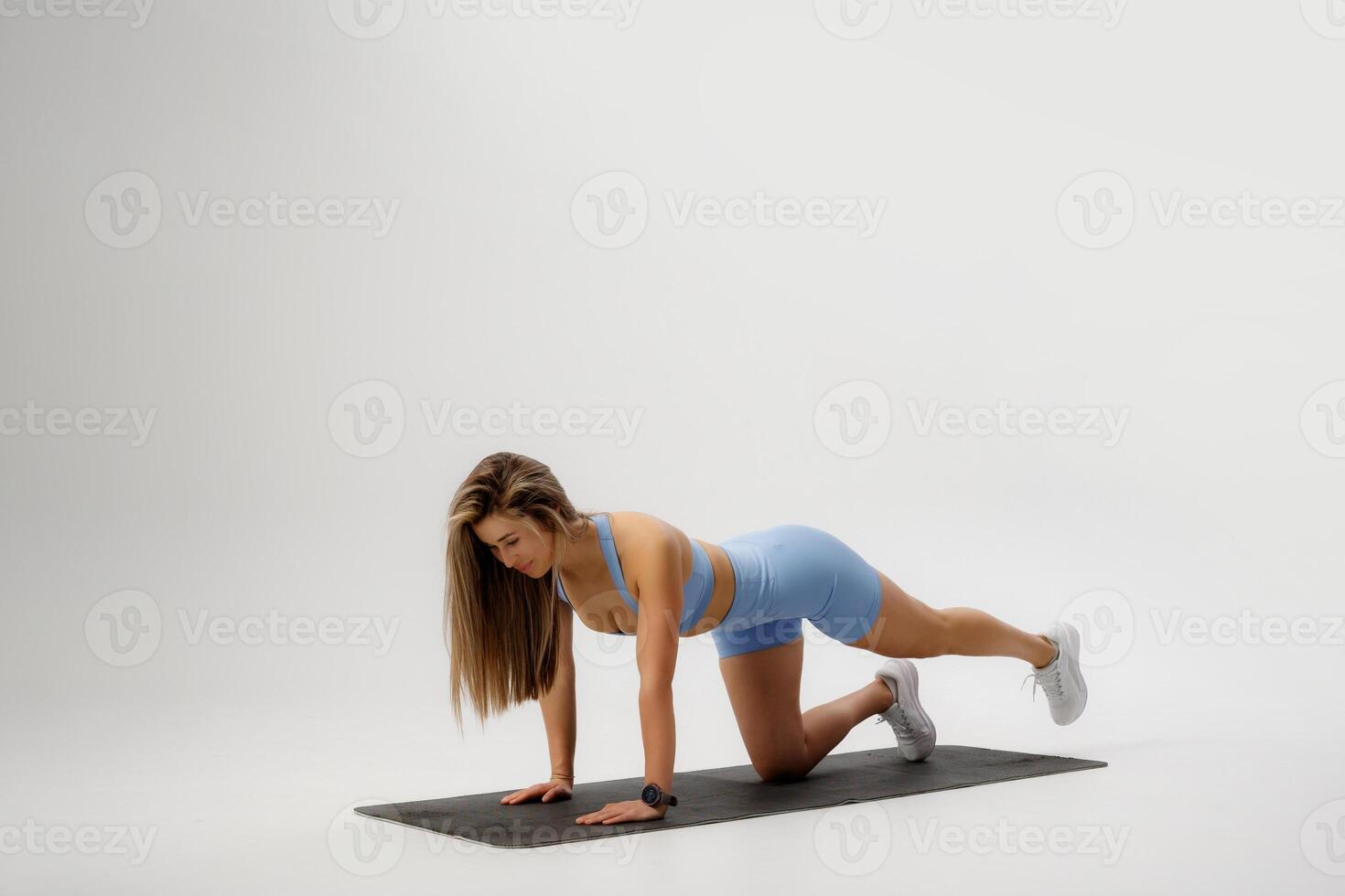 Woman performing an exercise routine on a mat in a studio during daylight hours for fitness and health photo