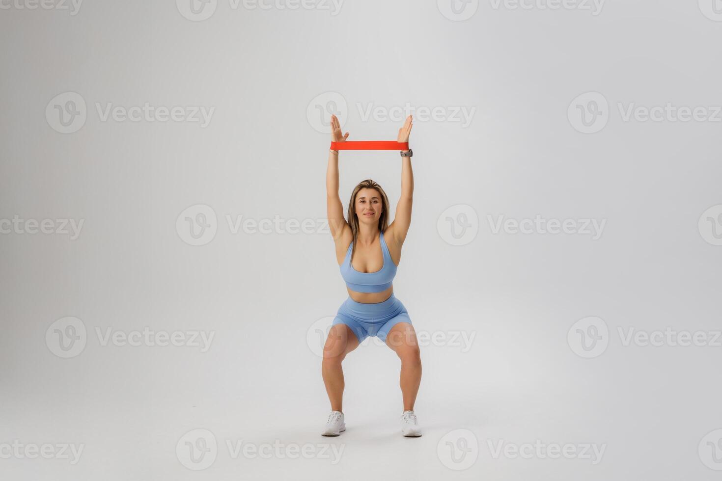 Woman performs a strength training exercise with a resistance band in a minimalist indoor space photo