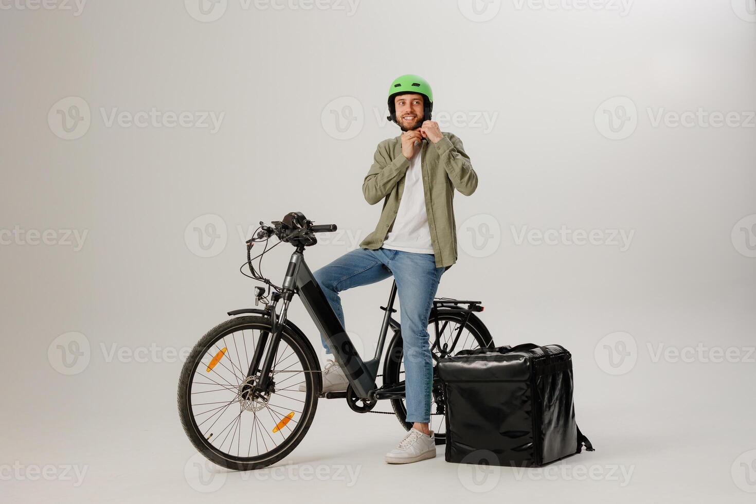 Delivery cyclist preparing for work with insulated bag and green helmet in urban studio setting photo