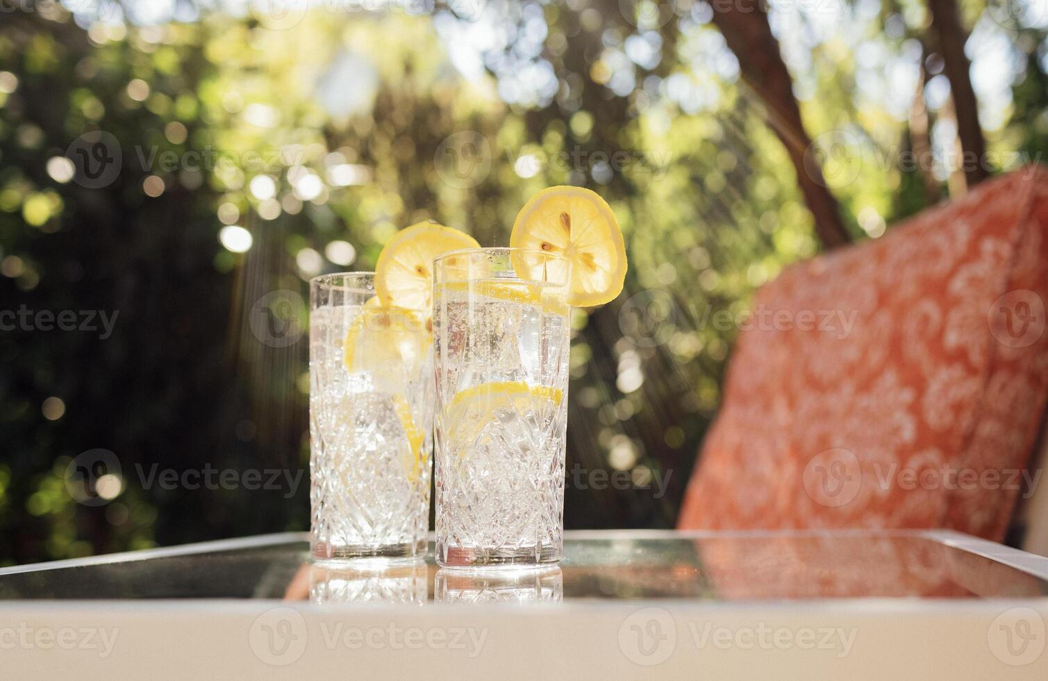 glasses with delicious cool lemonade on a glass table in the backyard of the house photo