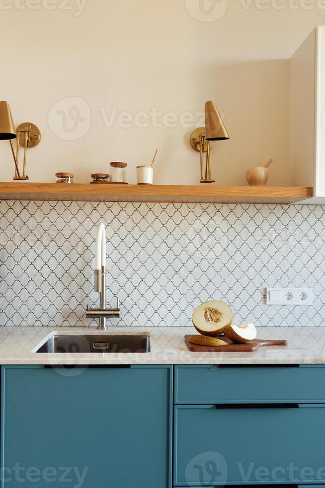 A modern kitchen with a blue set and a marble countertop photo