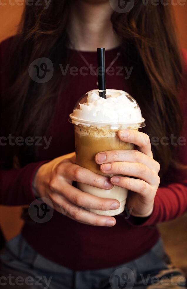 A young girl with long dark hair and casual clothes with a glass of drink photo