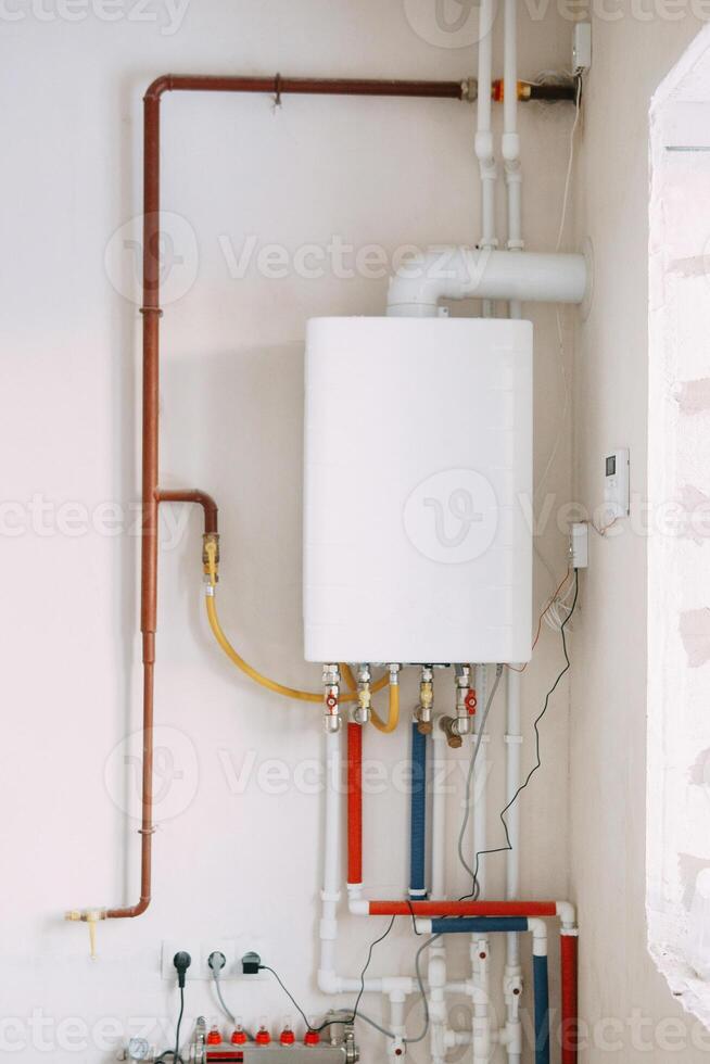 Installation of gas boiler with colored pipes equipped with valves and connectors for efficient supply of hot and cold water in residential water supply system photo