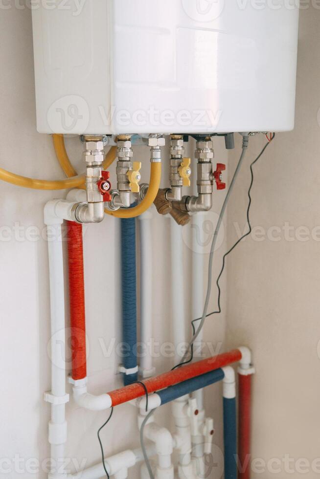 Installation of a gas boiler with colored pipes equipped with valves and connectors for efficient supply of hot and cold water in the residential water supply system. photo