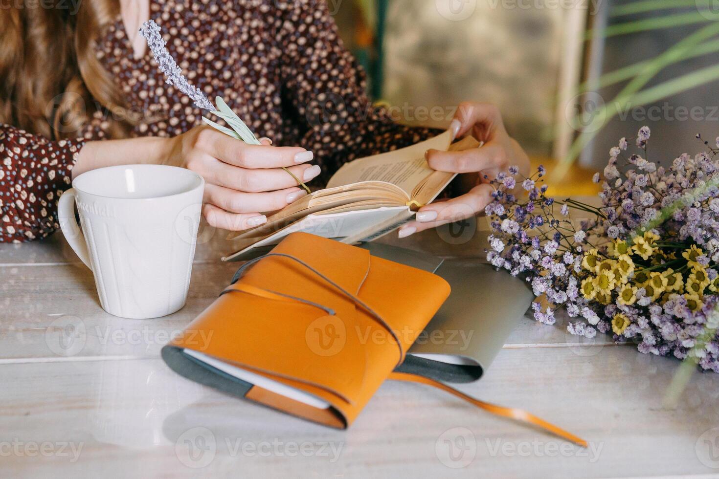 Woman enjoys reading at cozy table with floral notebook and warm coffee photo