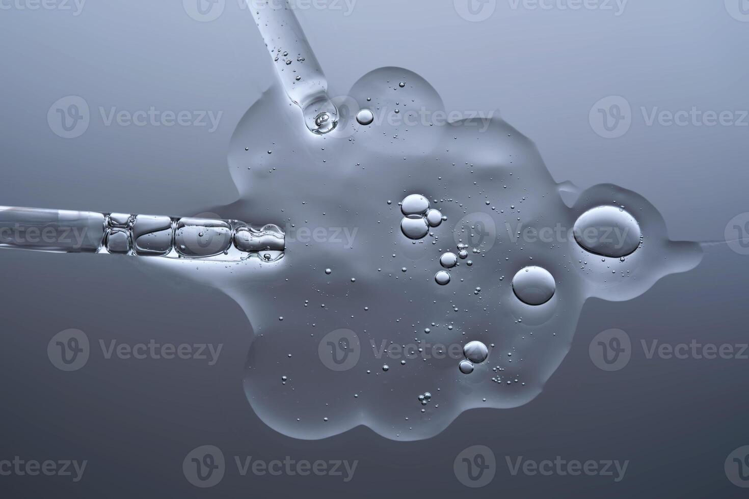 Two pipettes with a serum texture on a gray background. photo