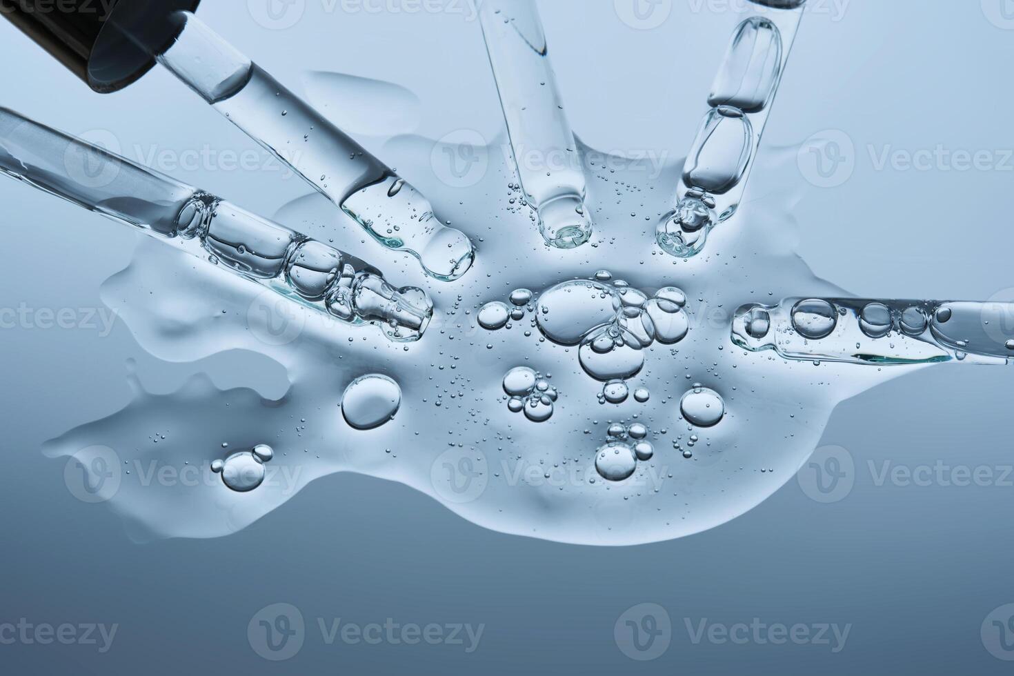 The serum flows from several pipettes into a single texture on a blue background. photo