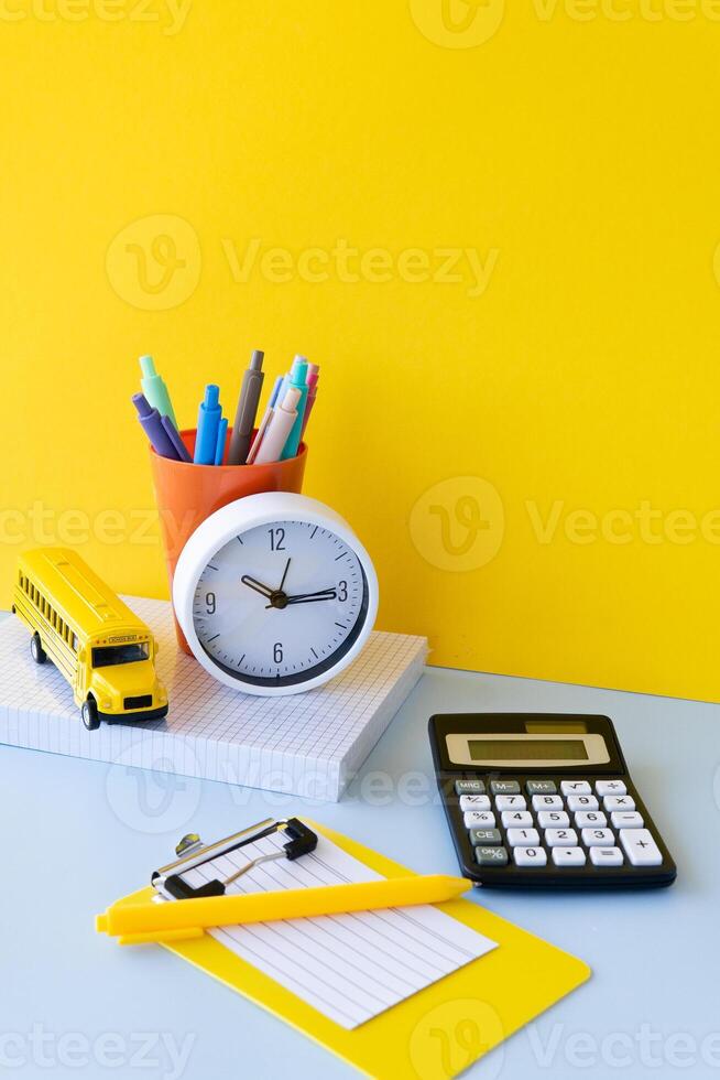Creative school supplies arrangement with paintbrushes colored pens school bus and notebooks on yellow background representing artistic learning bright stationery and modern educational mood photo