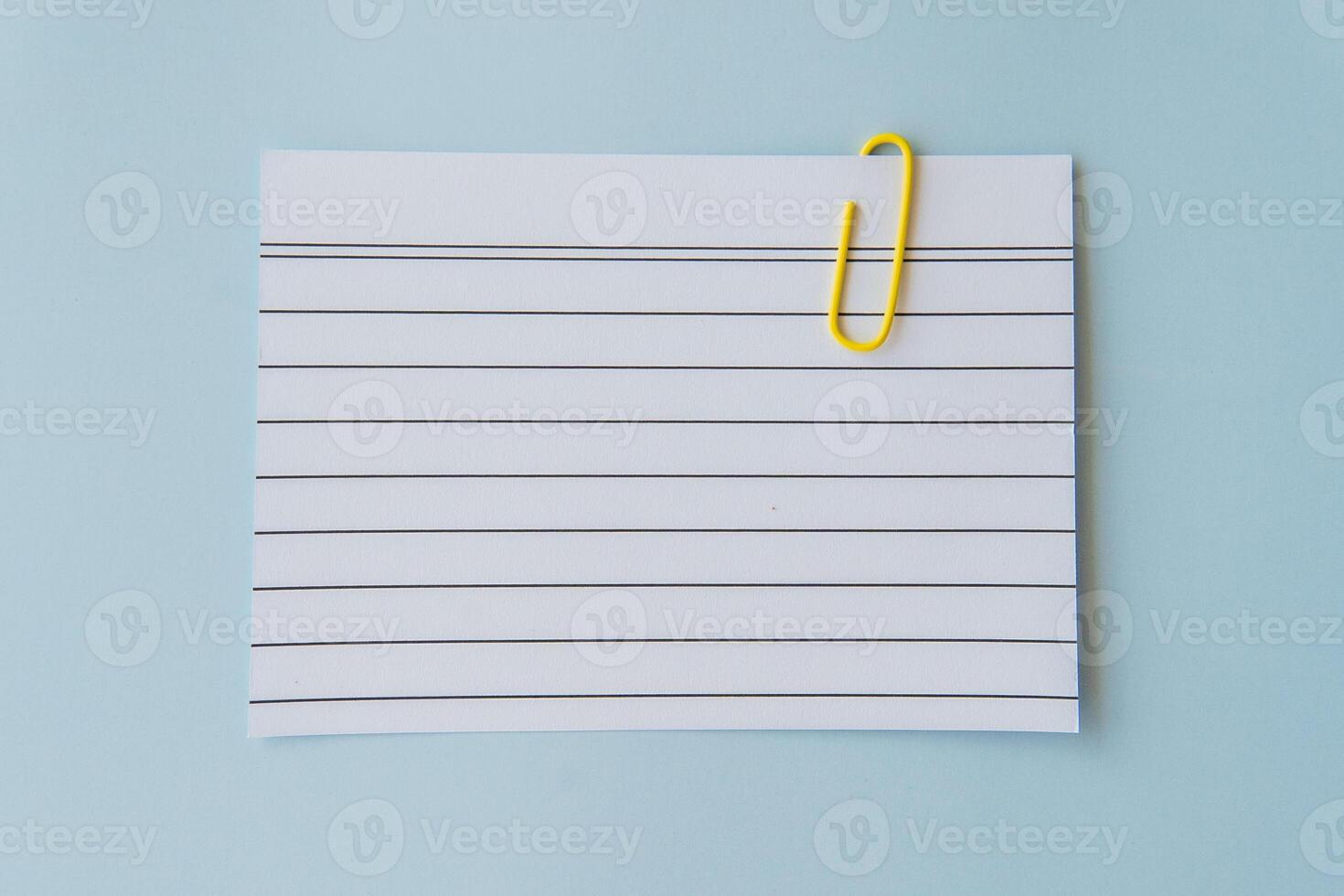 Minimal school paper concept with lined sheet and yellow paperclip on blue background symbolizing writing planning simplicity schoolwork education mood and creative organization for students photo