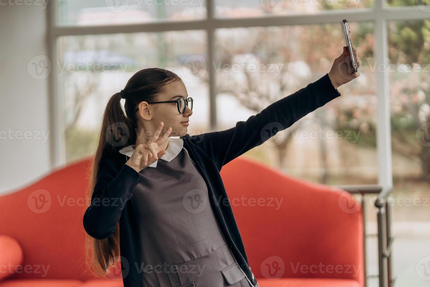 teen girl in school uniform taking selfie with smartphone on red couch expressing personality creativity and digital lifestyle in modern smart environment photo