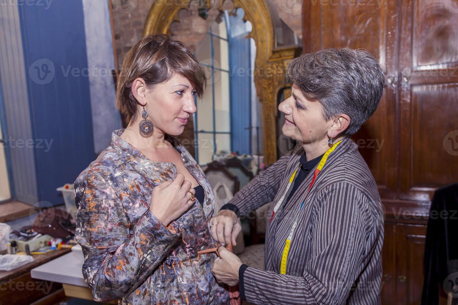 dressmaker and model chatting during fittings for a new dress in the fashion atelier photo