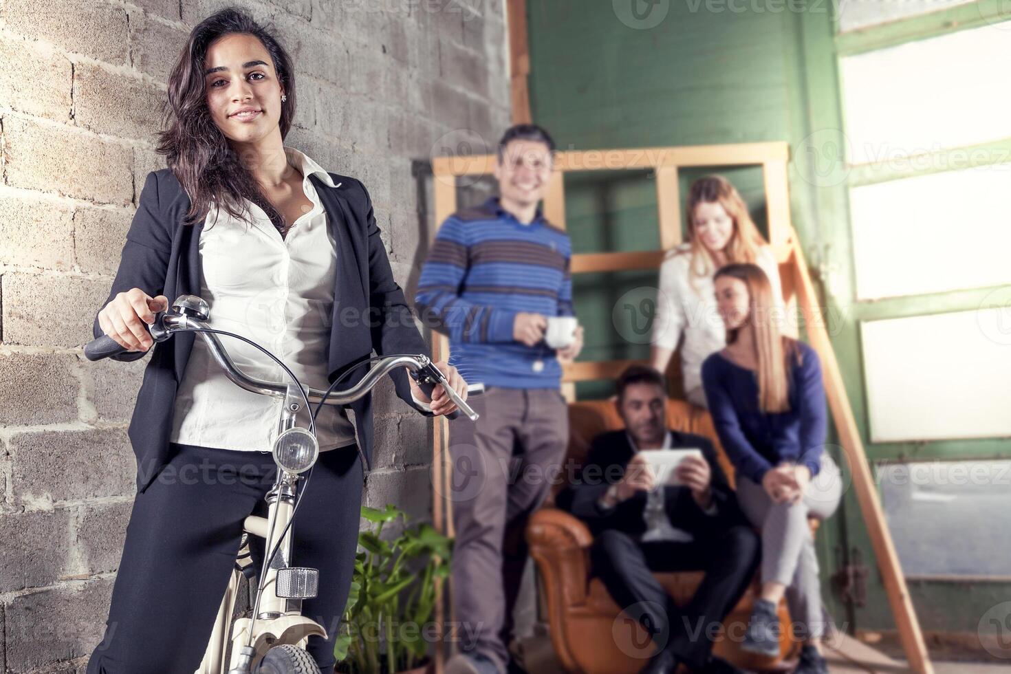 portrait of a young business woman on a bike posing with her team working together photo