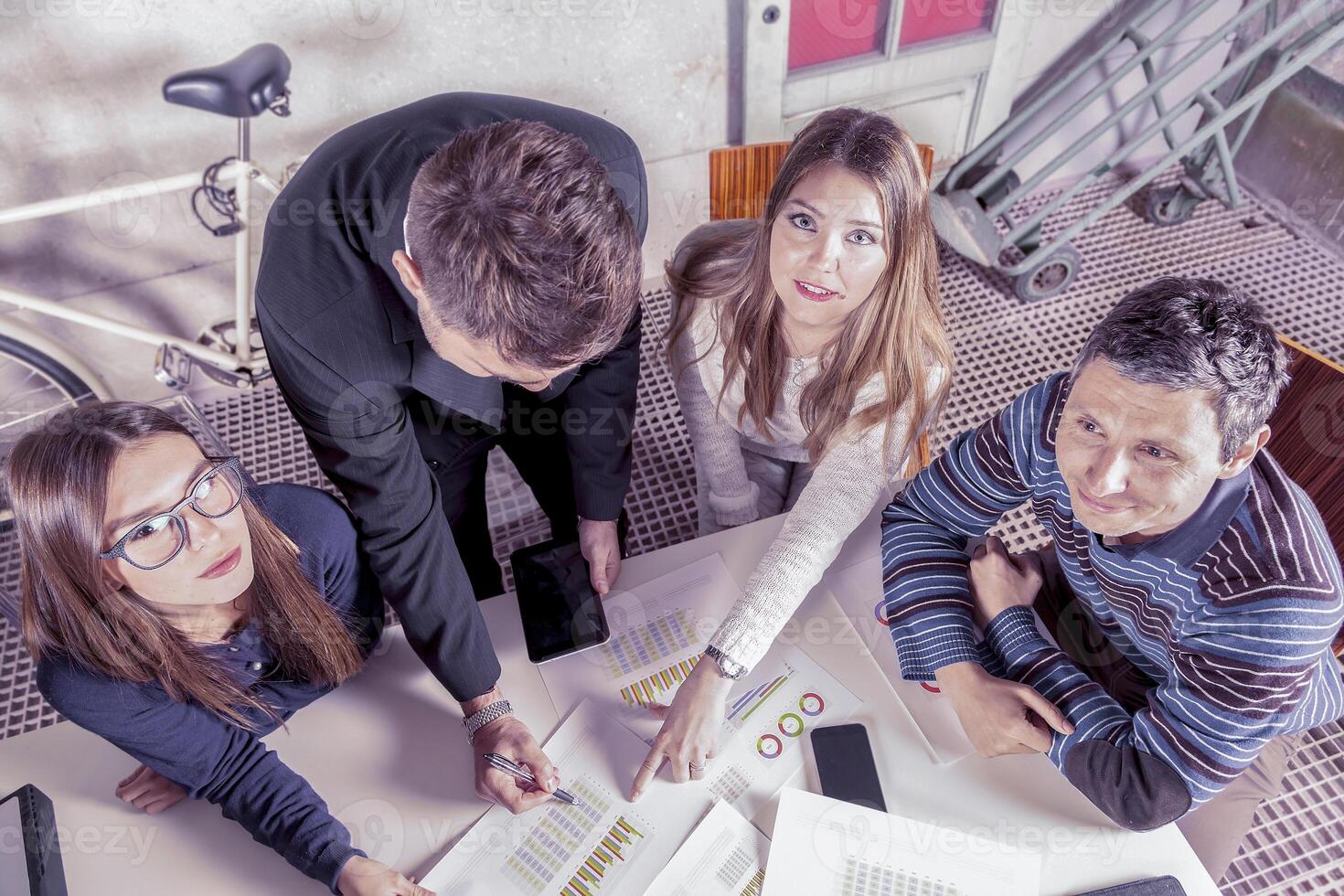 a group of young successful entrepreneurs in informal clothes consulting graphs and percentages in a creative office photo
