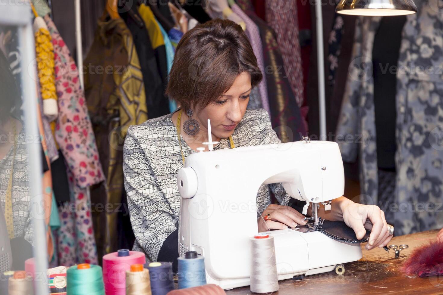 young seamstress is working with sewing machine in fashion atelier photo