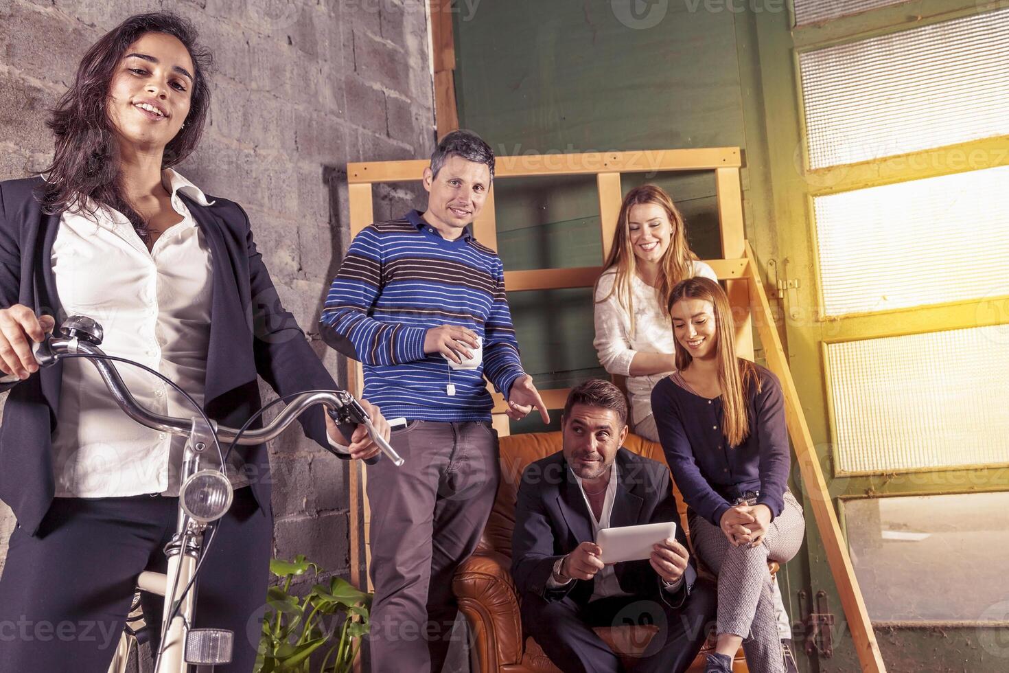 a group of young friendly successful business people in informal clothes posing for camera in a creative office photo