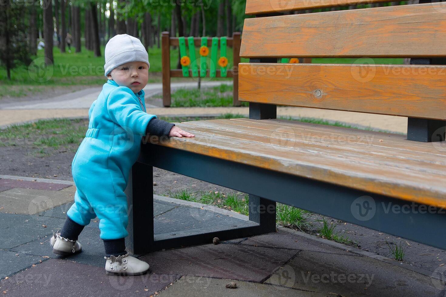 The child near a park bench in cool weather photo