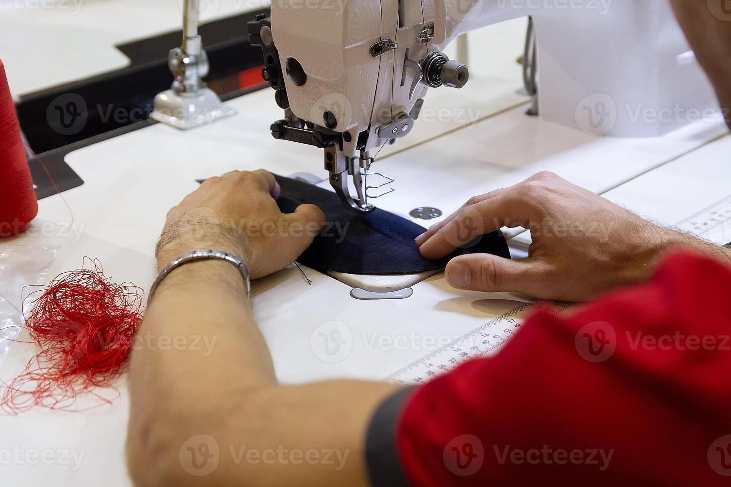 Men's hands near the sewing machine hold a cloth, in the process of sewing photo