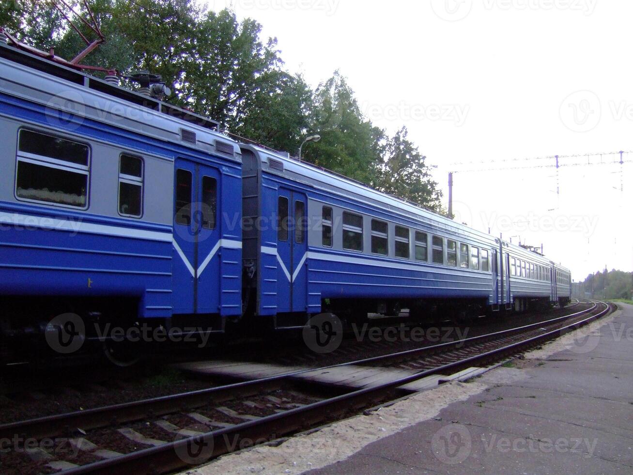 Blue train cars on a railway track in a quiet station during early photo