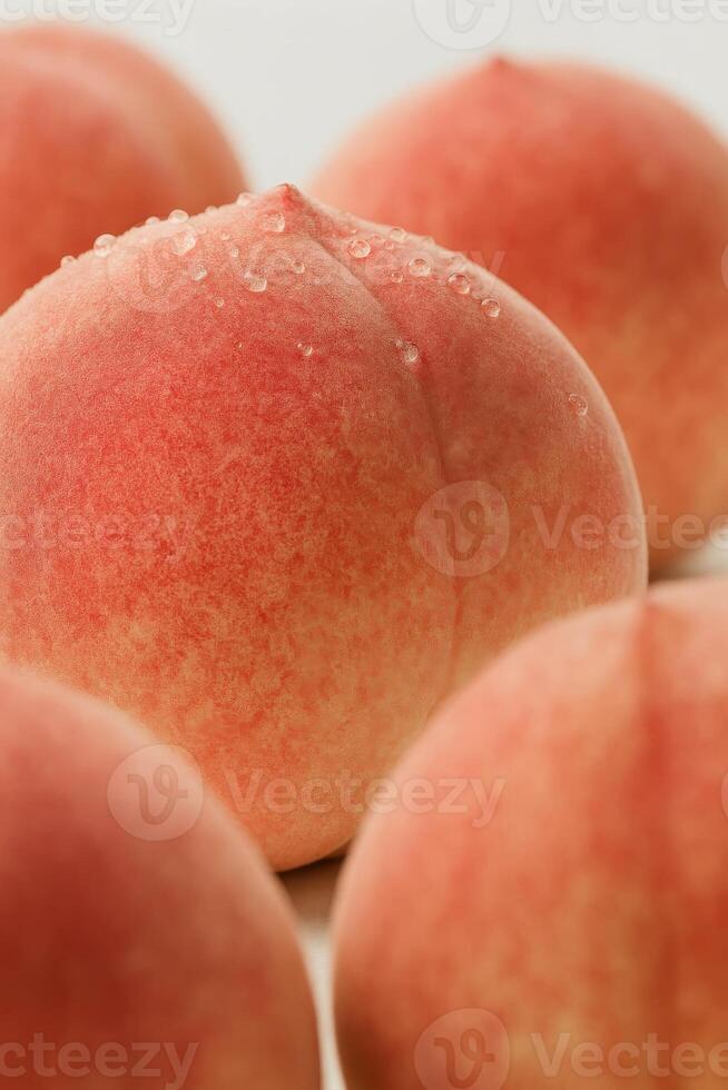 Extreme close-up of a ripe peach covered in fresh water droplets, surrounded by other peaches softly blurred in the foreground and background photo