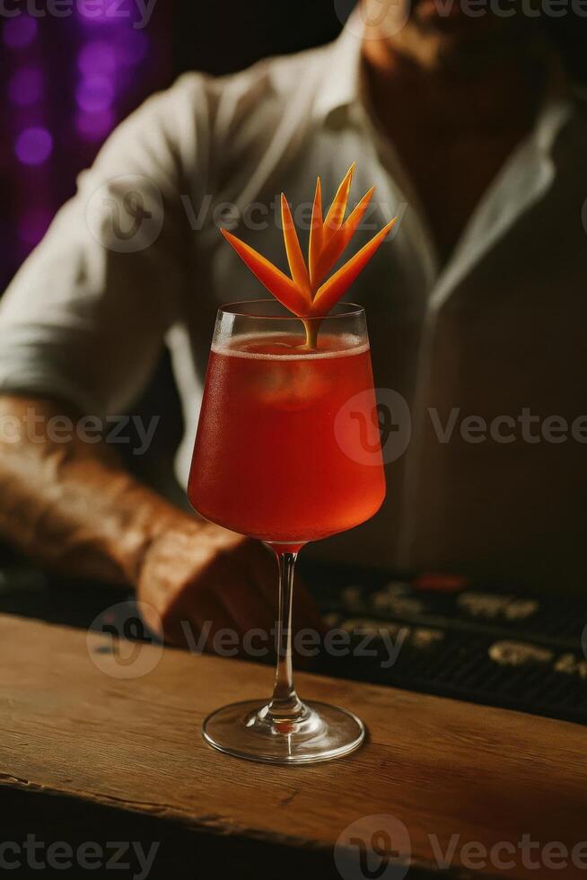 A vibrant red cocktail served in a tall-stemmed glass with ice cubes, elegantly garnished with a stylized bird-of-paradise flower carving. photo