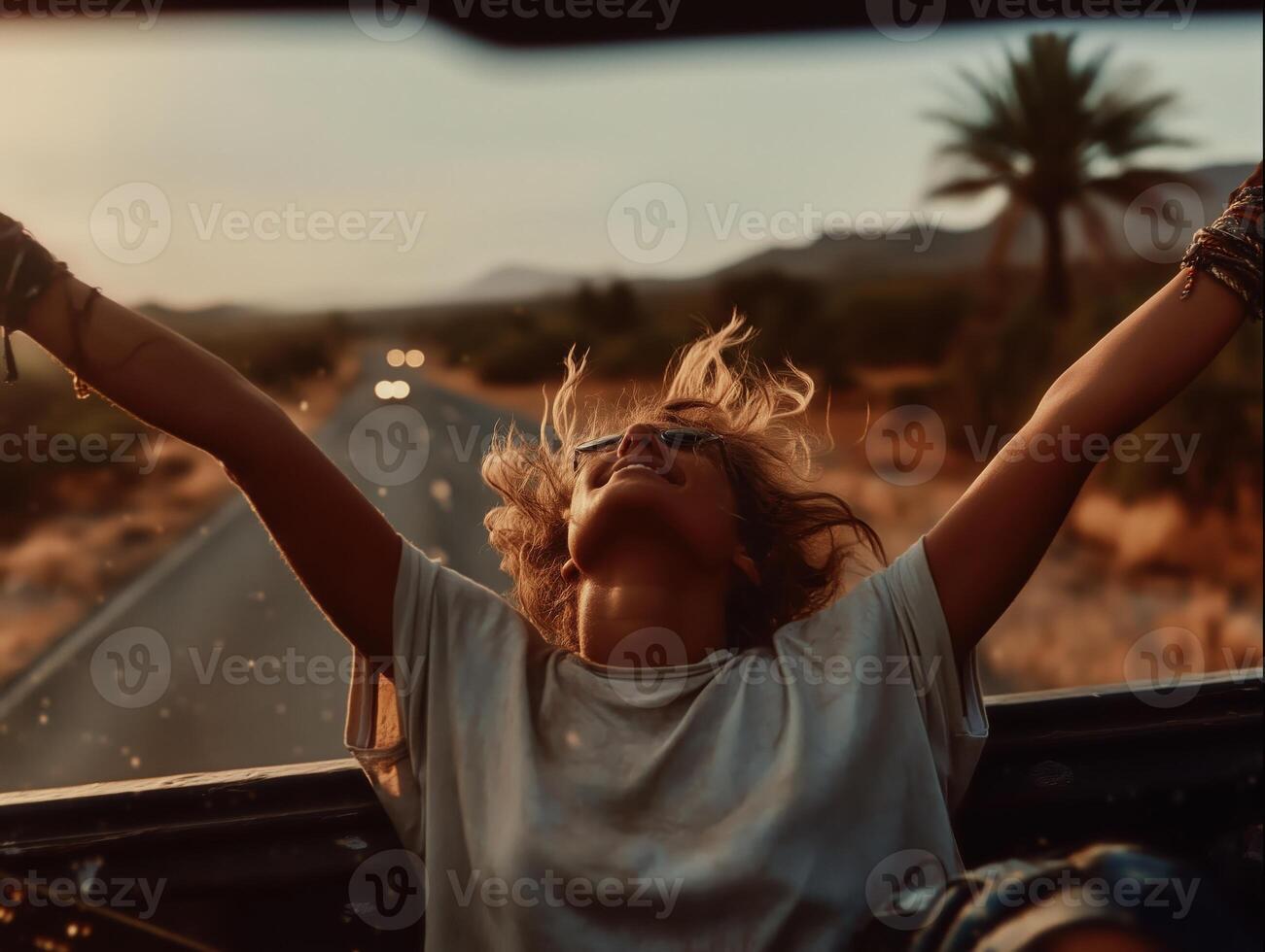 A cinematic shot of a young woman sitting in the back of a moving pickup truck with her arms spread wide and head tilted back, enjoying the wind and freedom. photo