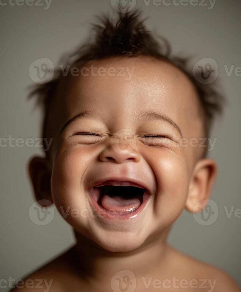 A joyful baby laughing with eyes closed, showing tiny baby teeth and deep dimples on the cheeks. photo