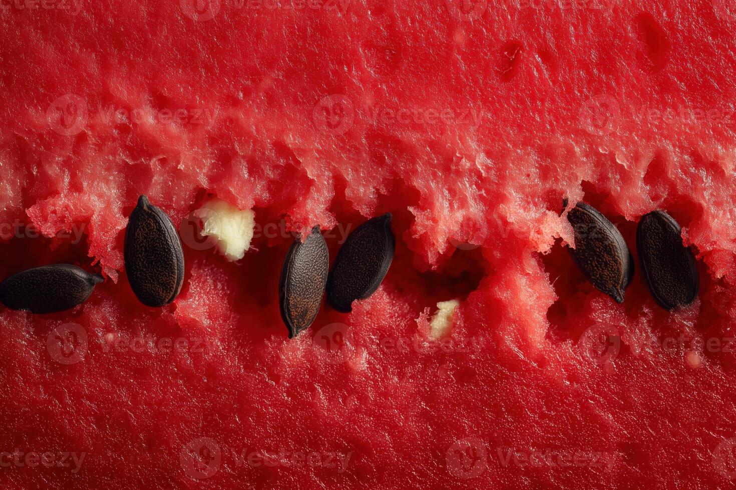 Macro photograph of ripe red watermelon pulp with a vertical line of black seeds centered in the frame. photo