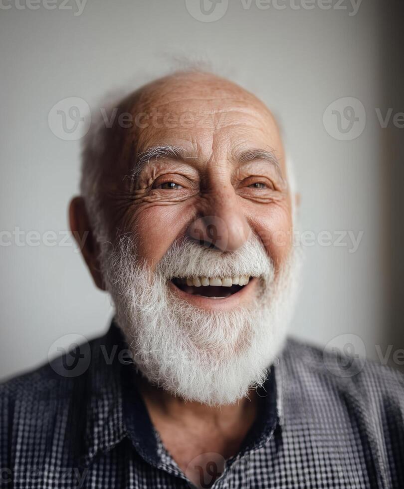 A close-up portrait of a cheerful elderly man with a full white beard and short white hair, wearing a checkered shirt. photo