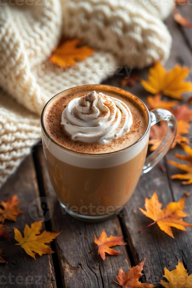 Coffee with whipped cream on a wooden table with autumn leaves photo