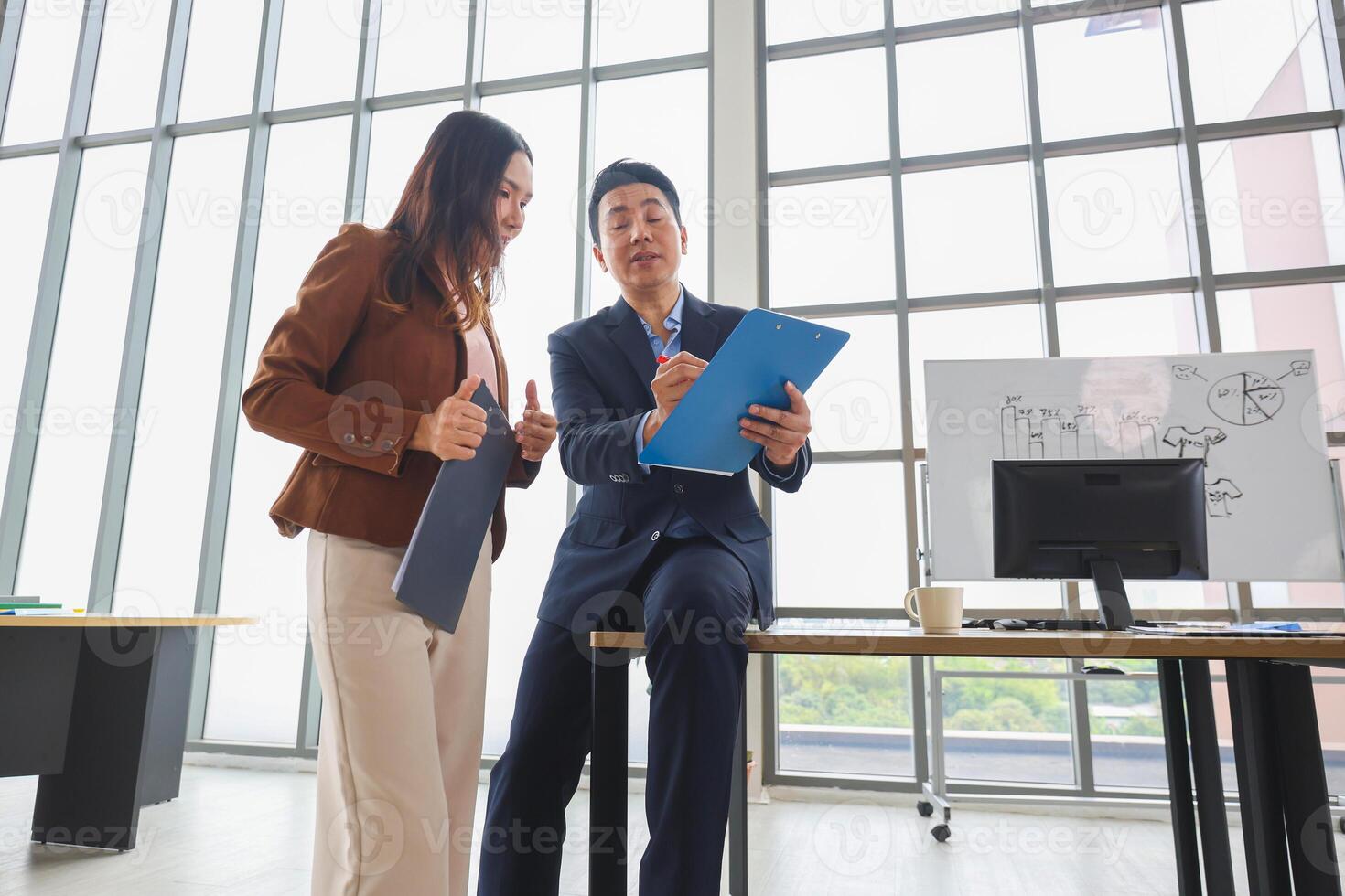 Asian businesspeople meeting in office, Two business professionals discussing documents in modern office, Team meeting and brainstorming concepts photo