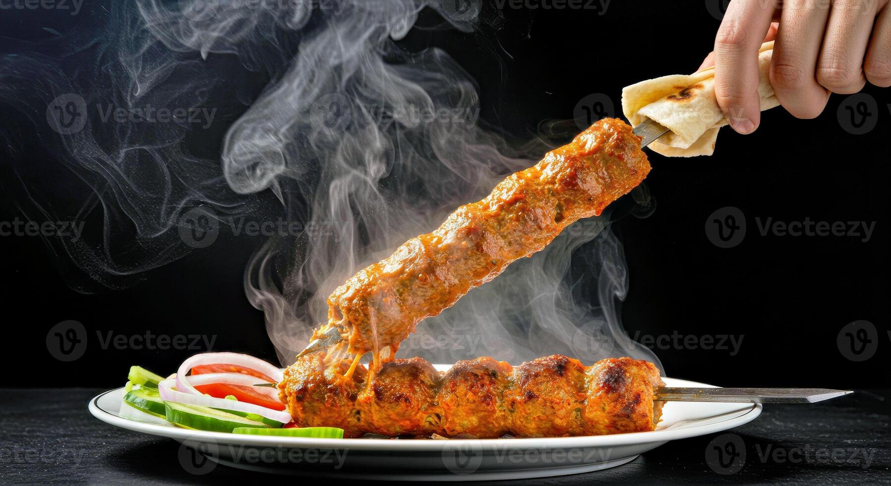 A person holding a skewer over a plate of meat photo