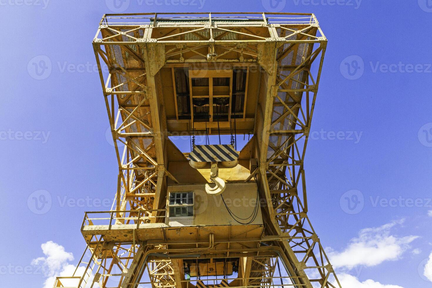 Bottom view of an industrial crane against a blue sky. photo