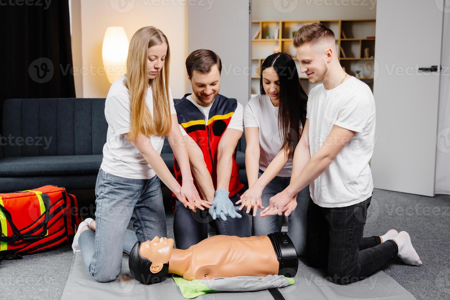 Man instructor helping to make first aid heart compressions with dummy during the group training photo