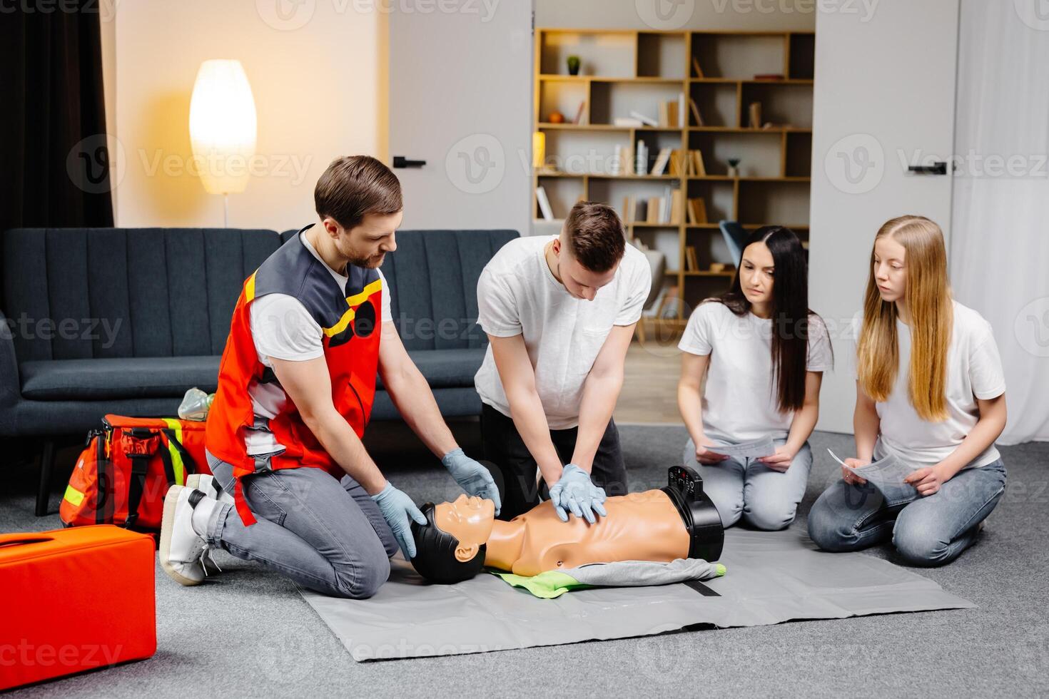 Man instructor helping to make first aid heart compressions with dummy during the group training class photo