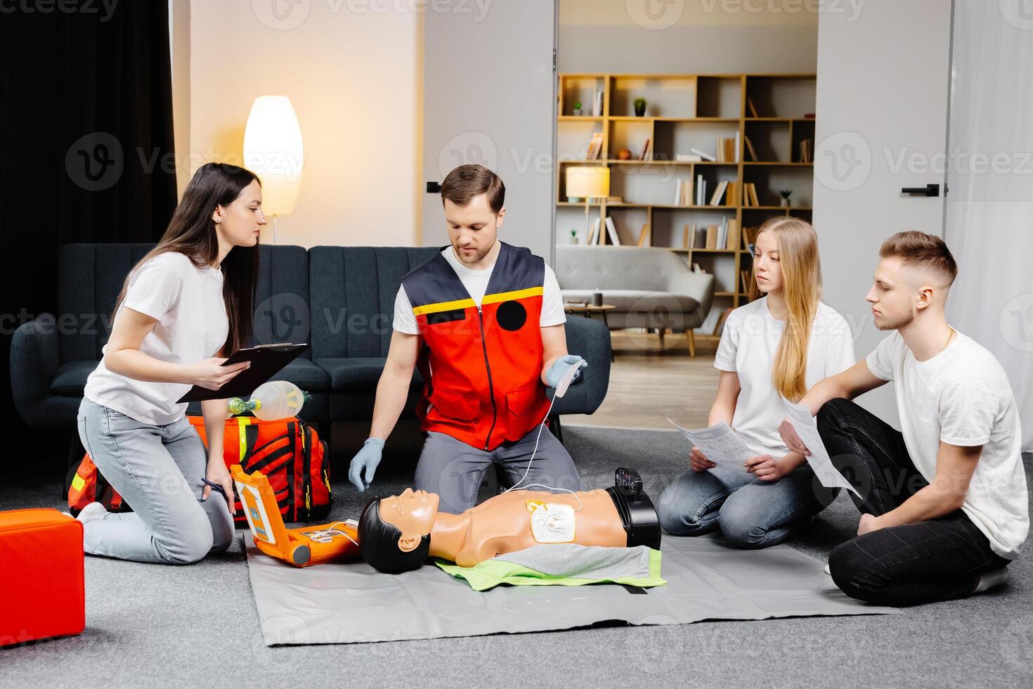 Young man instructor helping to make first aid heart compressions with dummy during the group training photo