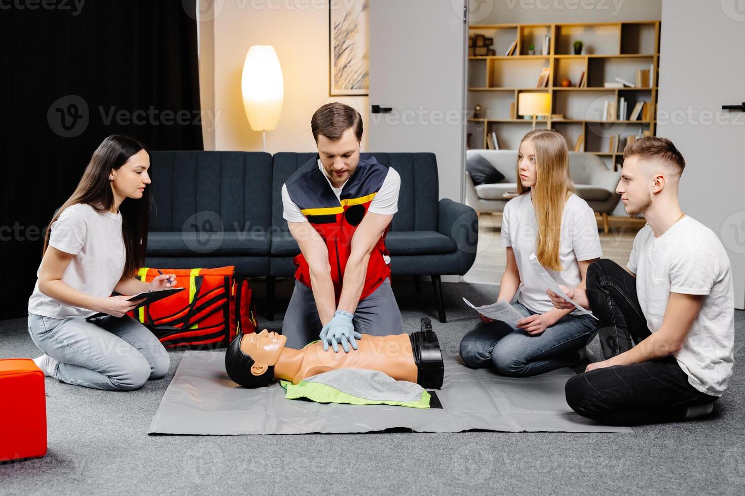 Young man instructor helping to make first aid heart compressions with dummy during the group training. photo