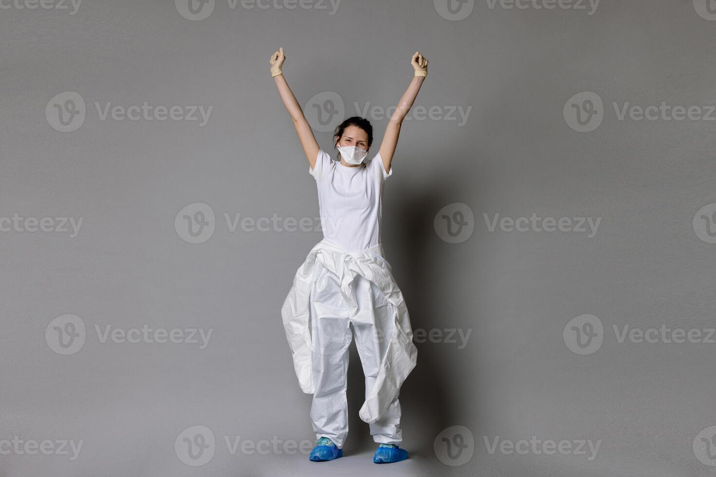 Frontliner in happy mood in hazmat suit. Covid-19 situation with grey clean background and copyspace. photo